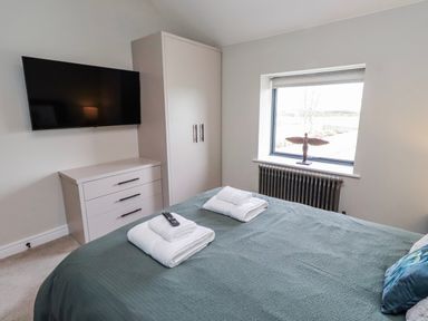 A bedroom with a bed and television at The Joiners Cottage in Birling near Warkworth