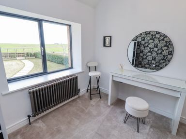 A bedroom with a window, a vanity table and two stools at The Joiners Cottage in Birling near Warkworth