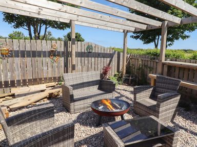 An outdoor seating area with a fire pit and gravel surface at The Joiners Cottage in Birling near Warkworth