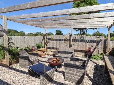 A garden with a seating area and fire pit at The Joiners Cottage in Birling near Warkworth