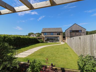 A garden with a lawn and pathway at The Joiners Cottage in Birling near Warkworth