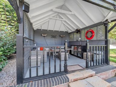 An outdoor seating area with a darts board and sofa at Oldfields in Bury St Edmunds