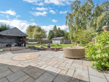 An outdoor patio with seating and a garden shed at Oldfields in Bury St Edmunds