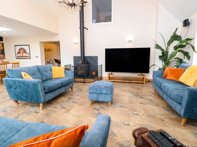 A living room with blue sofas and a television at Oldfields Bury St Edmunds