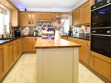 A kitchen with wood cabinets and an island at Oldfields in Bury St Edmunds