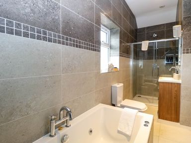 A bathroom with a bathtub, shower, toilet, and sink at Oldfields in Bury St Edmunds