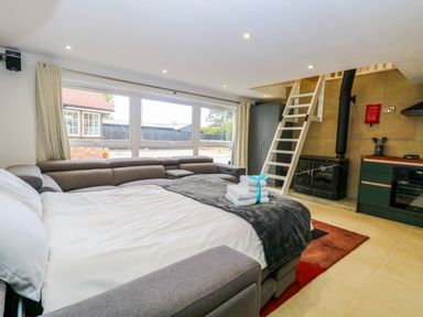 A living room with a sofa and kitchen unit at Oldfields Bury St Edmunds