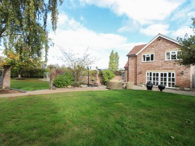A garden with a house and seating area at Oldfields in Bury St Edmunds