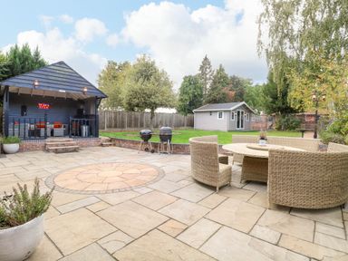 A garden with seating area, grill, and shed at Oldfields in Bury St Edmunds