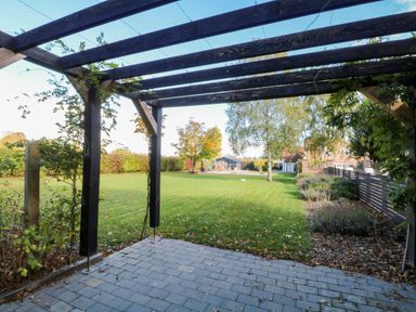 A garden view with a pergola and grass area at Oldfields in Bury St Edmunds