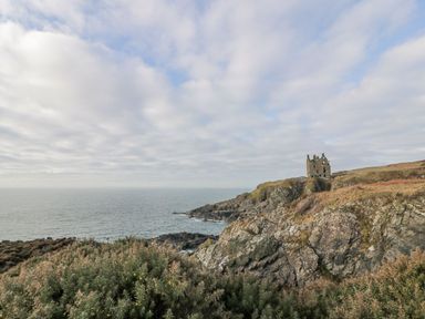 A coastal scene with a castle ruins near the ocean at Willow's Way in Stranraer