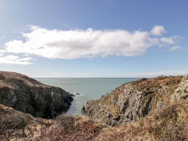 A view of cliffs and the ocean under a cloudy sky at Willow's Way in Stranraer