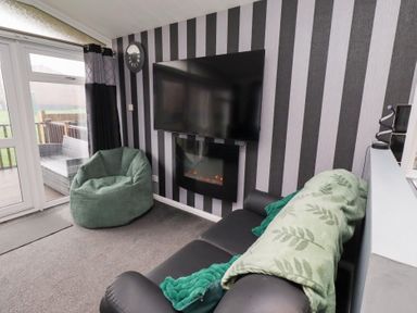 A living room with a television and a bean bag at Harper's Hideaway, Felmoor Holiday Park near Felton