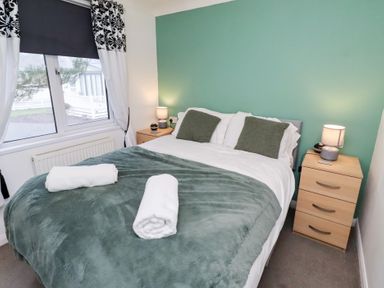 A bedroom with a bed and bedside tables at Harper's Hideaway Felmoor Holiday Park near Felton