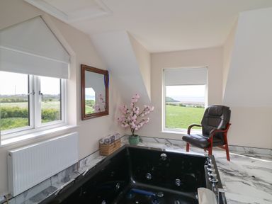 A bathroom with a bathtub and a chair at Ard Uisce @ Estuary Bliss, Duncannon, County Wexford