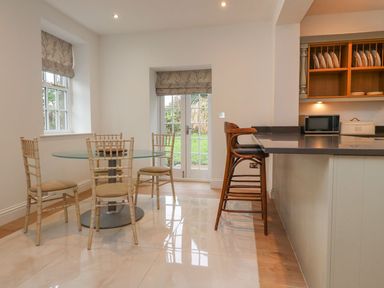 A dining room with a glass table and chairs at The Lodge House Dolphinholme near Galgate