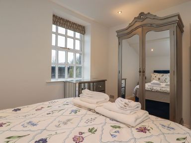A bedroom with a bed and wardrobe at The Lodge House in Dolphinholme near Galgate