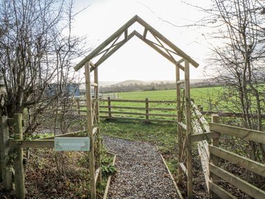 A pathway leading through a gateway labeled Honeysuckle at Honeysuckle Hut, Potto Grange Farm, Northallerton