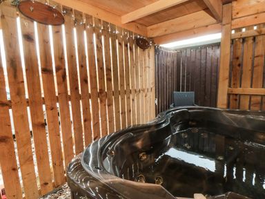 A hot tub surrounded by a wooden fence and a chair at Tooth Suite Yarm