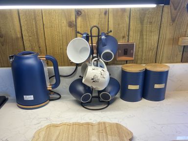 A kitchen countertop with a kettle and a cup rack with mugs at The Suffolk Hut in Lower Peover, Cheshire