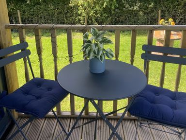 A table with chairs and a plant on a deck at The Suffolk Hut in Lower Peover, Cheshire
