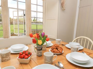 A dining room set with tableware and flowers at The Smithy in Stow on the wold