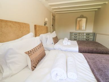 A bedroom with two beds and a dresser at The Smithy in Stow on the wold