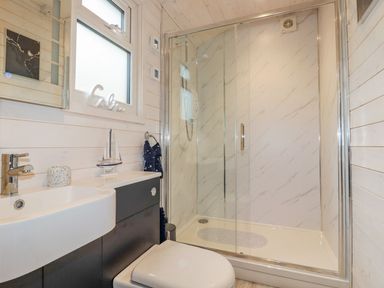 A bathroom with a shower unit, sink, and toilet at St. Chad's Lodge in Bodmin