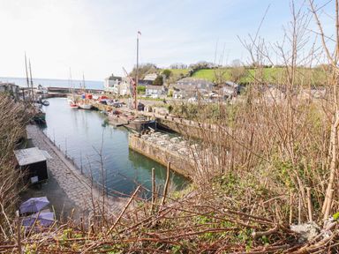 A view of boats in a harbor with buildings and hills at St. Chad's Lodge in Luxulyan