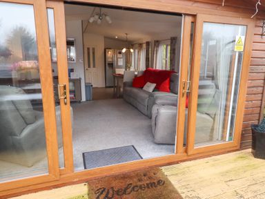 A living room with a sofa and dining area at Chloe's Cabin near Felmoor Holiday Park near Felton
