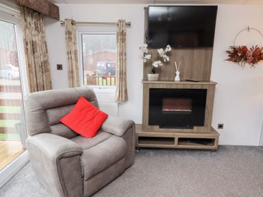 A living room with a chair and television at Chloe's Cabin near Felmoor Holiday Park near Felton