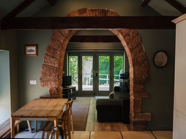 A living room with an arch leading to outdoor space at Carwinley Mill House Cottage Carwinley near Longtown