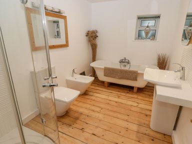 A bathroom with a bathtub, shower, toilet and sink at Rock House in Narberth