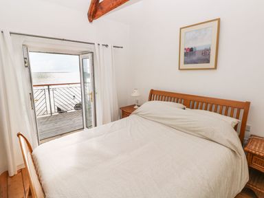A bedroom with a bed and doors leading to a balcony at Rock House in Narberth