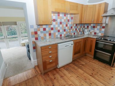 A kitchen with wooden cabinets and appliances at Kenvor in Newport, Pembrokeshire