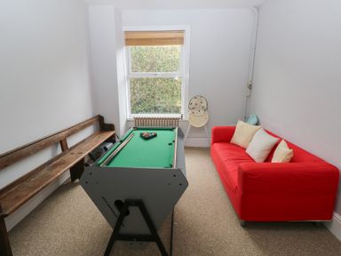 A game room with a pool table and a red sofa at Kenvor in Newport, Pembrokeshire