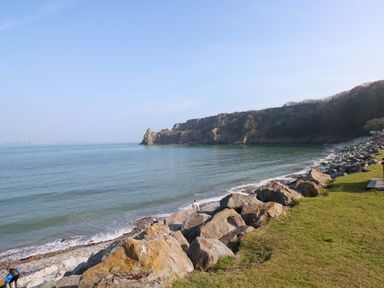 A shoreline with cliffs, rocks, and water at 82 Manorbier Park in Manorbier