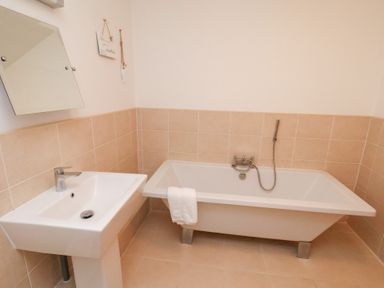 A bathroom with a bath tub and sink at One Union Mill - garden apartment in Whitby