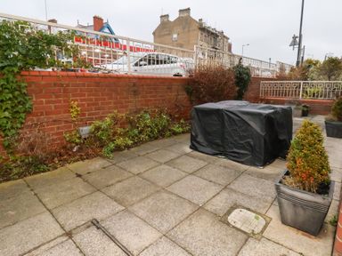 A garden with a paved area and potted plants at One Union Mill - garden apartment in Whitby