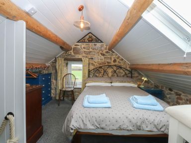 A bedroom with a double bed and a chair at Parc y Brenin Holidays, Abersoch