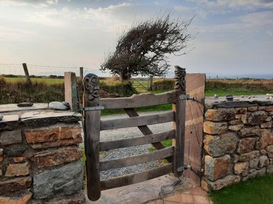An open wooden gate leading to a grassy area at Parc y Brenin Holidays, Cilan near Abersoch