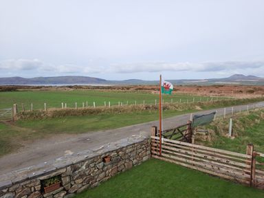 A view of a grassy field with a flag and gate at Parc y Brenin Holidays, Abersoch Cilan near Abersoch