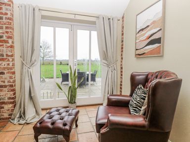 A conservatory with patio doors and seating area at Ivy Barn in Norwich