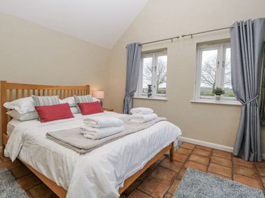A bedroom with a double bed and windows at Ivy Barn in Norwich