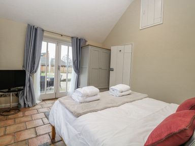 A bedroom with a bed and television at Ivy Barn in Norwich