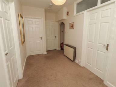 A hallway with multiple doors and a mirror at Kittiwake at No 20 Seahouses