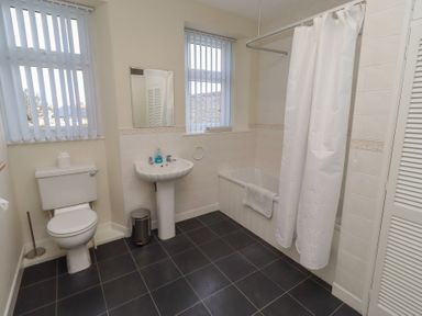 A bathroom with a toilet, wash basin, and bathtub at Kittiwake at No 20 Seahouses