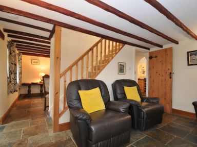 A living room with armchairs and a staircase at Little Blagdon in Beaworthy