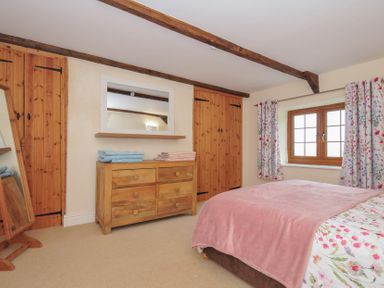 A bedroom with a bed, dresser, and curtains at Little Blagdon Beaworthy