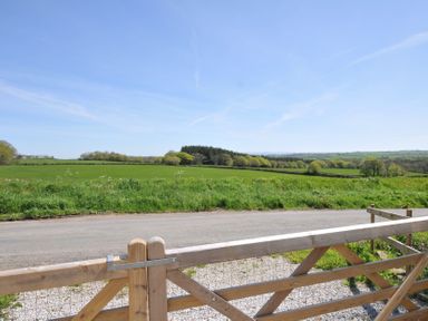 A view of fields and hills beyond a wooden gate at Little Blagdon in Ashwater